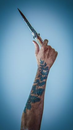 a person holding a pair of scissors in their hand with tattoos on it's arm