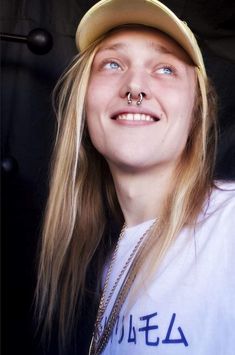 a woman with long hair wearing a yellow hat and piercing on it's nose