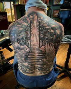 the back of a man's upper half with an open gate tattoo on it