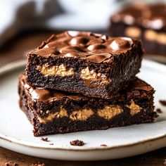 two pieces of brownie on a plate with chocolate frosting and peanut butter in the middle