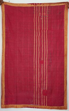 an old red and yellow cloth with white lines on the border, hanging from a wall