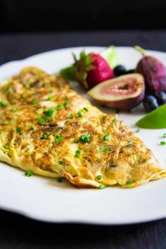 an omelet on a plate with fruit and vegetables