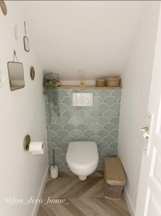 a white toilet sitting inside of a bathroom next to a wooden floor