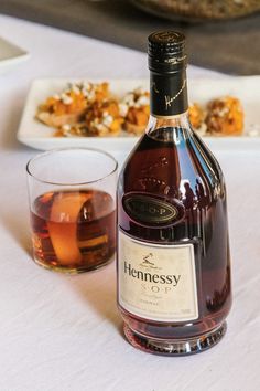 a bottle of hennessy on a table next to a glass and plate with food