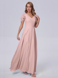 a woman in a long pink dress posing for the camera with her hands on her hips