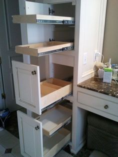 an open cabinet in a kitchen with marble counter tops