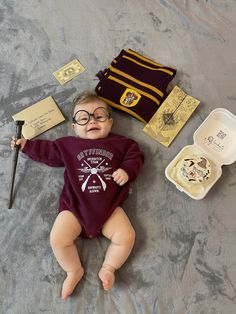 a baby laying on top of a bed next to harry potter items