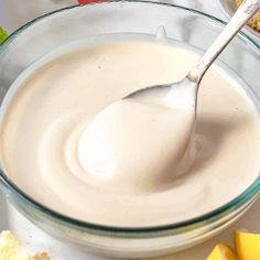 a glass bowl filled with cream next to sliced lemons