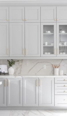 a white kitchen with marble counter tops and cabinets in front of the stove top oven