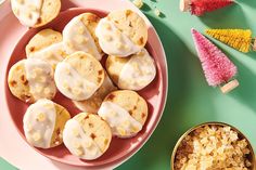 a pink plate topped with donuts covered in frosting next to a bowl of cereal