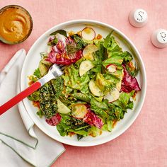 a white plate topped with lettuce and radishes next to two eggs