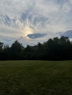 a field with trees and clouds in the background