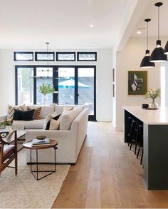 a living room filled with furniture next to a kitchen and dining room table on top of a hard wood floor