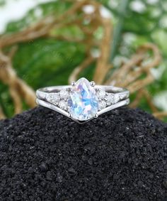 an engagement ring with a white topaz surrounded by greenery and rocks in the foreground