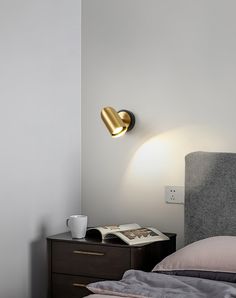 a lamp that is on the side of a wall next to a bed with pillows