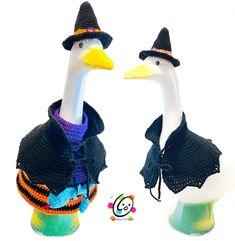 two plastic ducks wearing knitted hats and scarves, one is white and the other is black