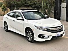 a white honda civic parked in front of a building on the side of the road