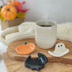 a cup of coffee sitting on top of a wooden tray next to two halloween decorations