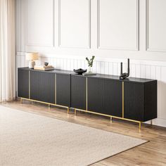 a living room with white walls and wooden flooring, two black sideboards on the wall