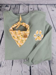 a green shirt with yellow flowers on it and a dog paw print bandana around the collar