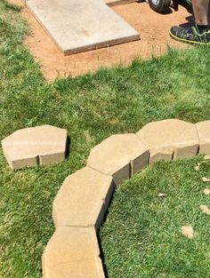 a man standing in the grass next to a brick walkway that has been cut into pieces