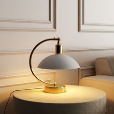 a table lamp sitting on top of a round table next to a couch in a living room