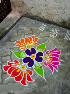 colorful flowers are painted on the ground next to a table with utensils and forks