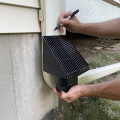 a man is using a tool to fix a gutter box on the side of a house