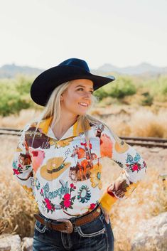 Yellow may have been considered an unlucky color in the past, but nowadays it's taking the rodeo world by storm. Let your style shine brighter than the sun with our I Need Sunshine & Fast Horses Button Down! This fashionable shirt—with its bright, colorful floral pattern and subtle tooled leather background—will make you the envy of the rodeo! We recommend pairing it with our Sunflower Tack Collection for the picture perfect hat to hoof look. Why are our TGC button downs a must have? Not only ar Spring Rodeo Button-up Shirt, Summer Long Sleeve Tops For Rodeo, Long Sleeve Tops For Summer Rodeo, Western Style Shirt For Rodeo In Spring, Spring Western Shirt For Ranch, Country Style Shirt For Summer Rodeo, Western Shirt For Spring Ranch Occasions, Western Style Shirt For Ranch In Spring, Western Shirt For Country Events In Spring