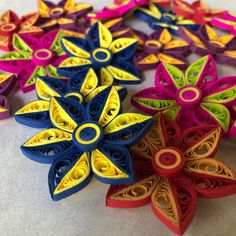 several colorful paper flowers on a white table top, with one flower cut out in the middle