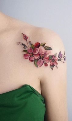 a woman's shoulder with pink flowers and green leaves on the left side of her body