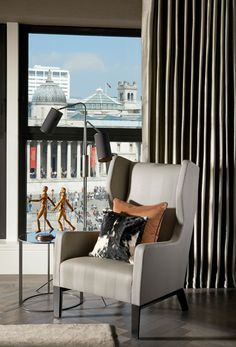 a living room filled with furniture next to a window covered in curtains and drapes