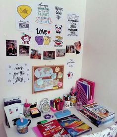 there are many pictures on the wall above the desk and in front of it is an assortment of books