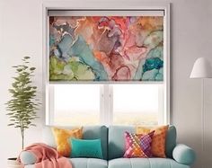 a living room filled with furniture and a large window covered in colorful art work on the wall