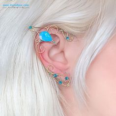 a close up of a person with white hair wearing ear piercings and blue stones