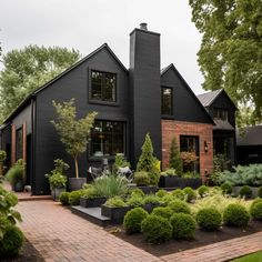 a black house with lots of trees and bushes