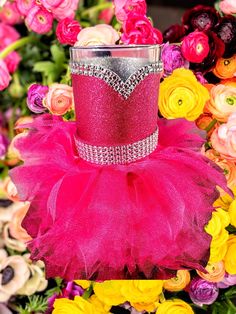 a pink tutu skirted cup holder sitting in front of colorful flowers and roses