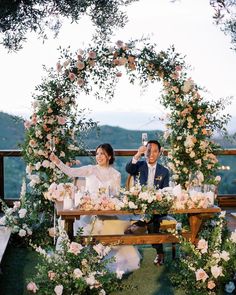 a man and woman sitting at a table with flowers