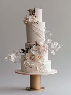 a three tiered wedding cake with flowers on top