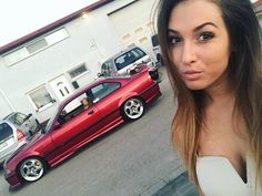 a woman standing in front of a red car