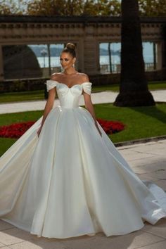 a woman in a white wedding dress is standing outside