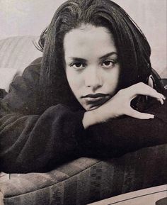 a black and white photo of a woman laying on a couch with her hand under her chin