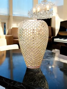 a vase sitting on top of a black table in front of a chandelier