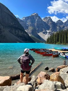 a person standing on rocks near boats in the water