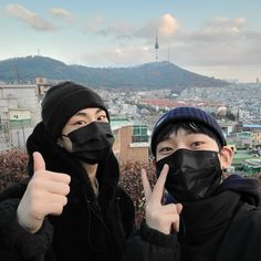 two people wearing black face masks and making the peace sign with their hands in front of them