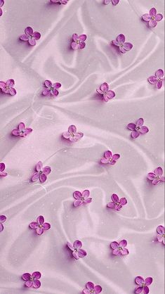 purple flowers floating in the water on top of a pink surface with white swirls