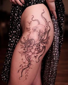 a woman's thigh with an octopus and flowers tattoo on the side of her leg