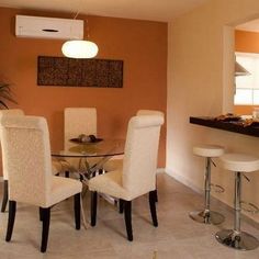 a dining room table with four chairs next to a counter and an air conditioner