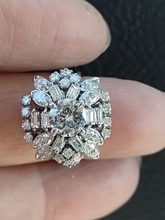 a close up of a person's hand holding a ring with diamonds on it