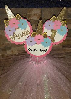 a pink and gold cake topper with unicorn ears